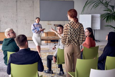 Photo for A group of young business professionals in a modern office attentively listens to colleague presentation, showcasing a dynamic and collaborative atmosphere as they exchange ideas and strive for - Royalty Free Image