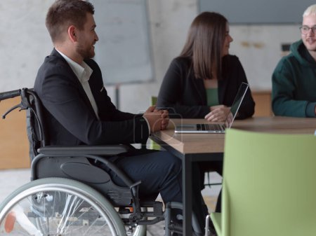 Foto de Foto de cerca de un grupo diverso de profesionales de negocios, incluyendo una persona con discapacidad, reunidos en una oficina moderna para una reunión productiva e inclusiva - Imagen libre de derechos