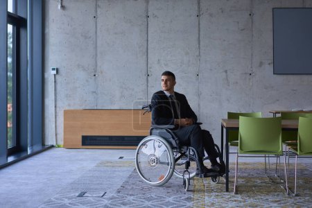 Foto de Empresario en silla de ruedas en una oficina moderna solo después de un día ajetreado. Foto de alta calidad - Imagen libre de derechos
