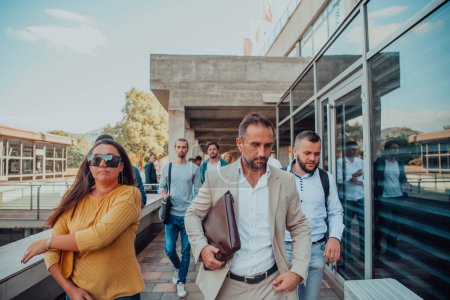 Photo for A diverse group of businessmen and colleagues walking together by their workplace, showcasing collaboration and teamwork in the company - Royalty Free Image