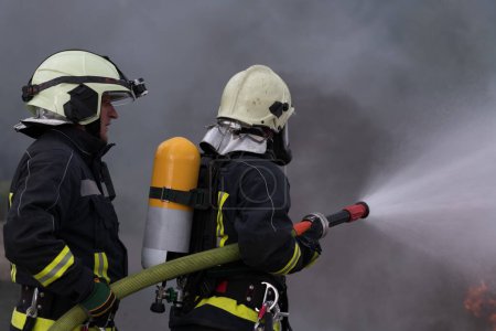 Foto de Bomberos que usan extintor de niebla de agua para luchar con la llama de fuego para controlar el fuego y no extenderse. Concepto de bombero industrial y de seguridad pública. Foto de alta calidad - Imagen libre de derechos