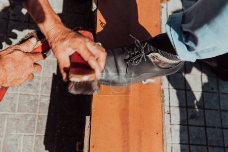 Foto de Un anciano pulido a mano y pintando un zapato negro en la calle. - Imagen libre de derechos