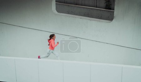 Téléchargez les photos : Femmes en vêtements de sport fonctionnant dans un environnement urbain moderne. Le concept d'un mode de vie sportif et sain. - en image libre de droit