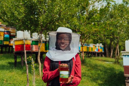 Foto de Retrato de una investigadora árabe en el departamento de apicultura de una granja de miel con un frasco de miel en la mano. - Imagen libre de derechos