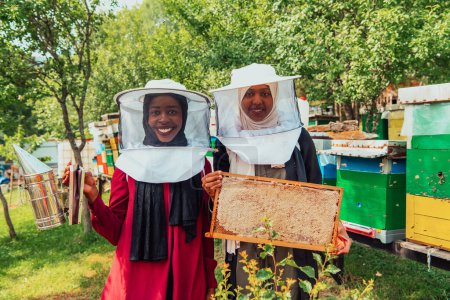Téléchargez les photos : Les investisseurs arabes vérifient la qualité du miel dans une grande ferme de miel dans laquelle ils ont investi leur argent. Le concept d'investissement dans les petites entreprises. - en image libre de droit