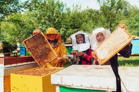 Téléchargez les photos : Les investisseurs arabes vérifient la qualité du miel dans une grande ferme apicole dans laquelle ils ont investi leur argent. Le concept d'investissement dans les petites entreprises. - en image libre de droit