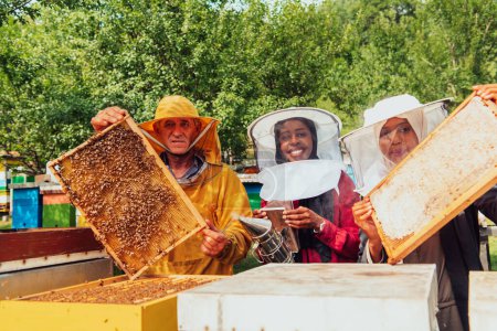 Foto de Arab investors checking the quality of honey on a large bee farm in which they have invested their money. The concept of investing in small businesses. - Imagen libre de derechos