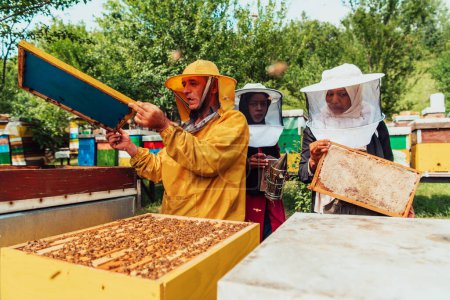 Téléchargez les photos : Deux investisseurs arabes vérifient la qualité du miel dans une grande ferme apicole dans laquelle ils ont investi leur argent. Le concept d'investissement dans les petites entreprises. - en image libre de droit