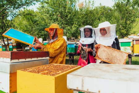 Téléchargez les photos : Deux investisseurs arabes vérifient la qualité du miel dans une grande ferme apicole dans laquelle ils ont investi leur argent. Le concept d'investissement dans les petites entreprises. - en image libre de droit