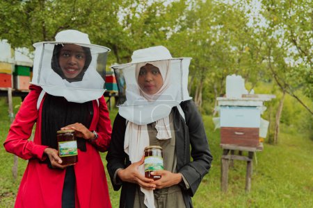 Foto de Portrait of an Arab investors holding a jar of honey in their hands while standing in front of a large honey farm. The concept of investing in small businesses. - Imagen libre de derechos