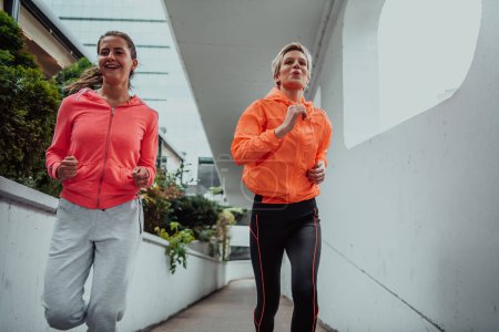 Foto de Dos mujeres en ropa deportiva corriendo en un entorno urbano moderno. El concepto de un estilo de vida deportivo y saludable. - Imagen libre de derechos