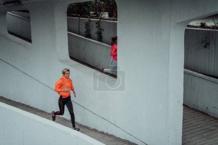 Photo for Two women in sports clothes running in a modern urban environment. The concept of a sporty and healthy lifestyle. - Royalty Free Image