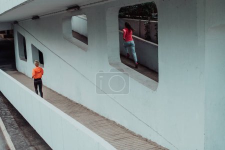 Téléchargez les photos : Deux femmes en tenue de sport qui courent dans un environnement urbain moderne. Le concept d'un mode de vie sportif et sain. - en image libre de droit