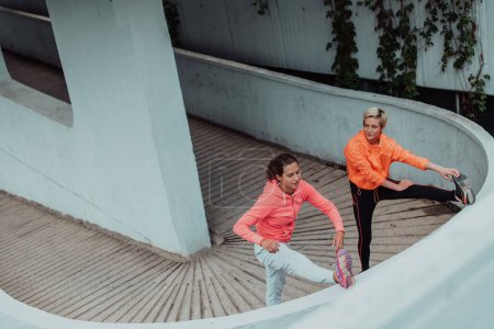 Photo for Two women warming up together and preparing for a morning run in an urban environment. Selective focus . - Royalty Free Image