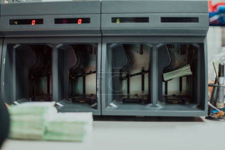 Photo for Bank employees using money counting machine while sorting and counting paper banknotes inside bank vault. Large amounts of money in the bank. - Royalty Free Image