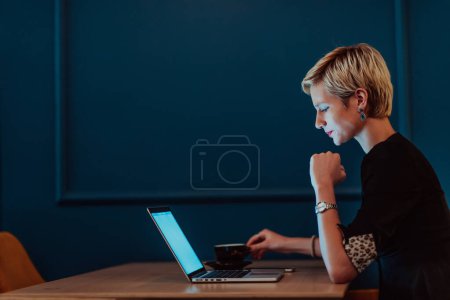 Téléchargez les photos : Businesswoman sitting in a cafe while focused on working on a laptop and participating in an online meetings. Selective focus - en image libre de droit