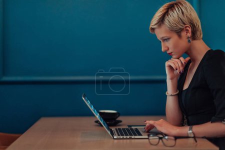Foto de Mujer de negocios sentada en un café mientras se concentra en trabajar en una computadora portátil y participar en reuniones en línea. Enfoque selectivo - Imagen libre de derechos