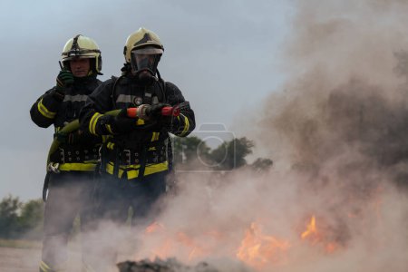 Foto de Los bomberos luchan contra la llama de fuego para controlar el fuego y no para extenderse. Concepto de bombero industrial y de seguridad pública. Tráfico o accidente de coche de rescate y ayuda a la acción - Imagen libre de derechos