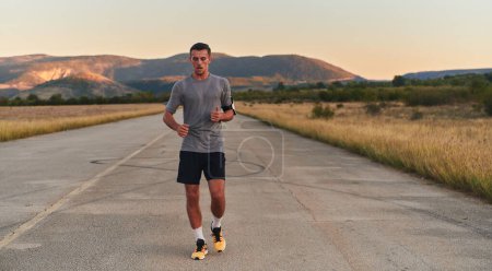 Téléchargez les photos : Un jeune homme beau qui court tôt le matin, motivé par son engagement pour la santé et la forme physique. Photo de haute qualité - en image libre de droit