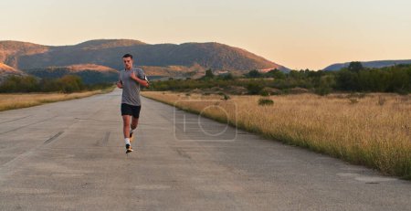 Téléchargez les photos : Un jeune homme beau qui court tôt le matin, motivé par son engagement pour la santé et la forme physique. Photo de haute qualité - en image libre de droit
