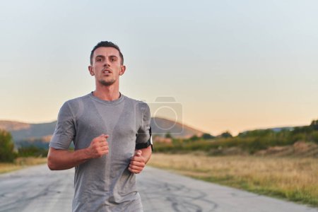 Ein junger, gutaussehender Mann läuft in den frühen Morgenstunden, angetrieben von seinem Engagement für Gesundheit und Fitness. Hochwertiges Foto