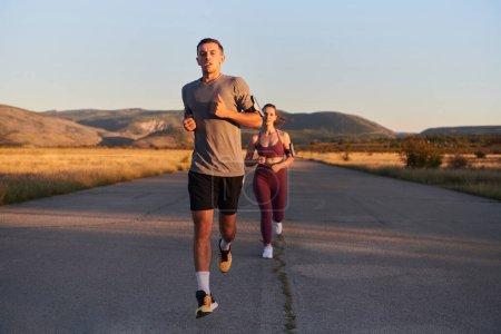 Photo for A handsome young couple running together during the early morning hours, with the mesmerizing sunrise casting a warm glow, symbolizing their shared love and vitality. - Royalty Free Image