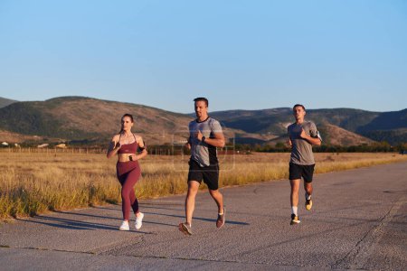 Photo for A group of young athletes running together in the early morning light of the sunrise, showcasing their collective energy, determination, and unity . - Royalty Free Image
