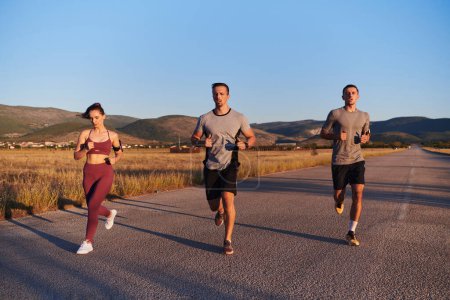 Foto de Un grupo de jóvenes atletas corriendo juntos a la luz del amanecer, mostrando su energía colectiva, determinación y unidad . - Imagen libre de derechos