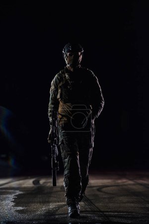 Photo for A professional soldier in full military gear striding through the dark night as he embarks on a perilous military mission. - Royalty Free Image