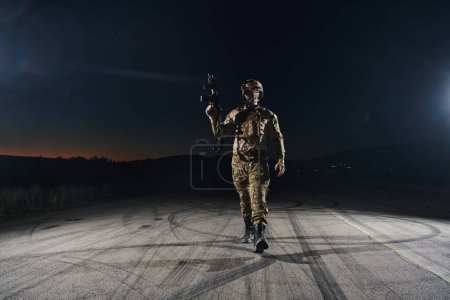 Téléchargez les photos : Un soldat professionnel en équipement militaire complet traversant la nuit noire alors qu'il entreprend une mission militaire périlleuse. - en image libre de droit