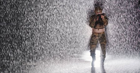 Foto de Soldado del ejército en uniformes de combate con un rifle de asalto, portaplatos y casco de combate que va en una misión peligrosa en una noche lluviosa - Imagen libre de derechos