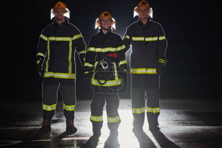 Téléchargez les photos : Un groupe de pompiers professionnels marchant de nuit dans une mission de sauvetage, leurs pas déterminés et leurs expressions intrépides reflétant leur bravoure inébranlable et leur engagement inébranlable à - en image libre de droit