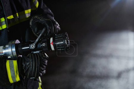 Photo for Firefighter using a water hose to eliminate a fire hazard. Team of firemen in the dangerous rescue mission - Royalty Free Image