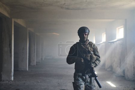 Foto de Un soldado profesional en un edificio abandonado muestra valentía y determinación en una campaña de guerra. - Imagen libre de derechos
