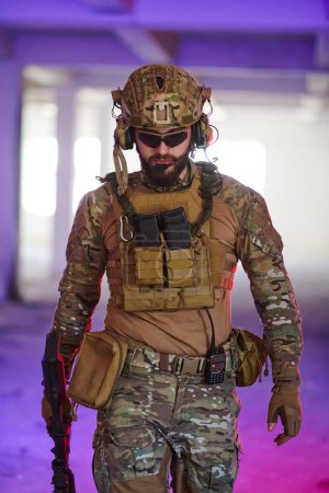Foto de Un soldado profesional emprende una peligrosa misión en un edificio abandonado iluminado por luces azul neón y púrpura. - Imagen libre de derechos