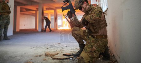 Photo for Soldier in action near window changing magazine and take cover. - Royalty Free Image
