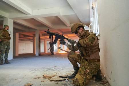 Foto de Soldado en acción cerca de la ventana cambiante revista y ponerse a cubierto. - Imagen libre de derechos