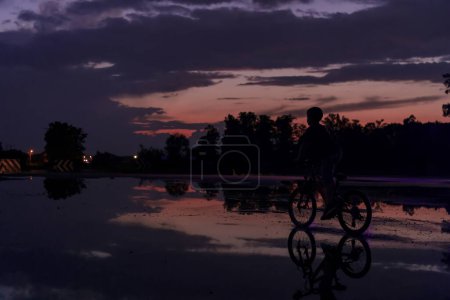 Photo for Lonely children silhouette on bike, boy riding bicycle on reflective water. Background beautiful sunset - Royalty Free Image
