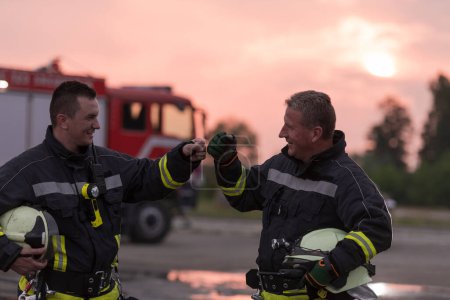 Téléchargez les photos : Pompier utilisant talkie walkie à la voiture de secours camion de pompiers d'action de la circulation et l'équipe de pompiers en arrière-plan. Photo de haute qualité - en image libre de droit