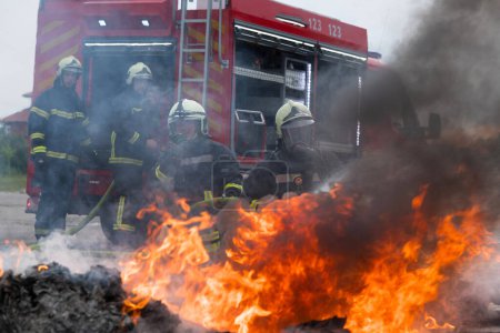 Téléchargez les photos : Les pompiers combattent la flamme du feu pour contrôler le feu et non pour se propager. Concept de sécurité industrielle et publique des pompiers. Secours et aide en cas d'accident de voiture ou de circulation - en image libre de droit