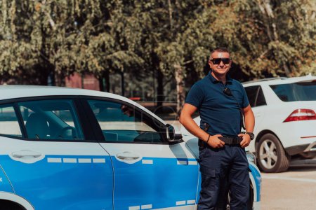 Foto de Un policía patrulla la ciudad. Un oficial de policía con gafas de sol patrullando en la ciudad con un coche oficial de policía. - Imagen libre de derechos