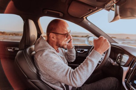 Foto de El conductor recibe información feliz mientras habla en el teléfono inteligente mientras conduce el coche. - Imagen libre de derechos