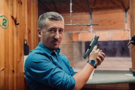 Photo for A man practices shooting a pistol in a shooting range while wearing protective headphones. - Royalty Free Image