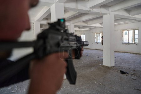 Photo for In an abandoned building, a terrorist takes aim with a rifle at a military opponent, engaged in a fierce battle for territorial control, embodying the dangers and tensions of the conflict - Royalty Free Image