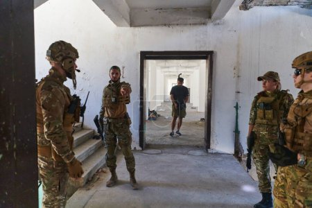 Foto de Grupo de soldados discute tácticas militares mientras están situados en un edificio abandonado, planificando meticulosamente sus movimientos con enfoque y determinación - Imagen libre de derechos