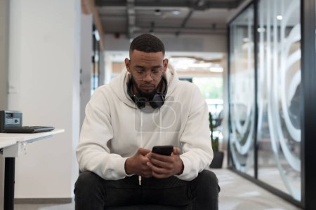 Téléchargez les photos : Dans un environnement de bureau moderne, un homme d'affaires afro-américain travaille diligemment sur son ordinateur portable, incarnant la détermination, l'ambition et la productivité dans son environnement professionnel.. - en image libre de droit