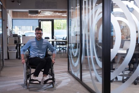 Foto de En una gran corporación moderna, un decidido hombre de negocios en silla de ruedas navega por un pasillo, encarnando el empoderamiento y la inclusión en el mundo corporativo - Imagen libre de derechos