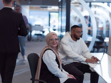 Foto de En un entorno de oficina moderno, un hombre de negocios afroamericano y su colega musulmán, vistiendo un hiyab, participan en discusiones colaborativas, abordando diversas tareas de negocios y resolviendo problemas. - Imagen libre de derechos