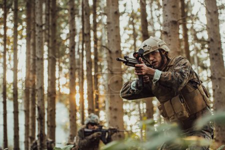 Photo for A group of modern warfare soldiers is fighting a war in dangerous remote forest areas. A group of soldiers is fighting on the enemy line with modern weapons. The concept of warfare and military - Royalty Free Image