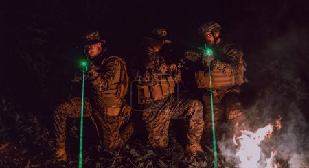 Téléchargez les photos : Escouade de soldats en action sur la mission de nuit en utilisant les feux de visée laser concept d'équipe militaire. - en image libre de droit